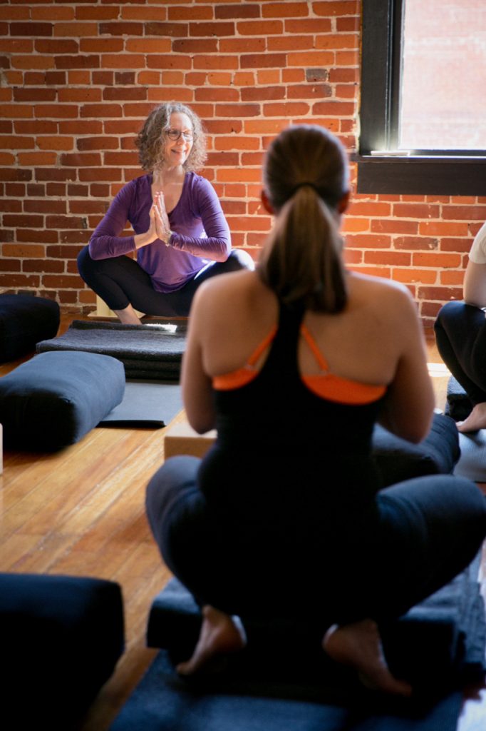 Carol Gray leads a prenatal yoga class at MamaSpace Yoga. Students are practicing Malasana or Frog Squat.