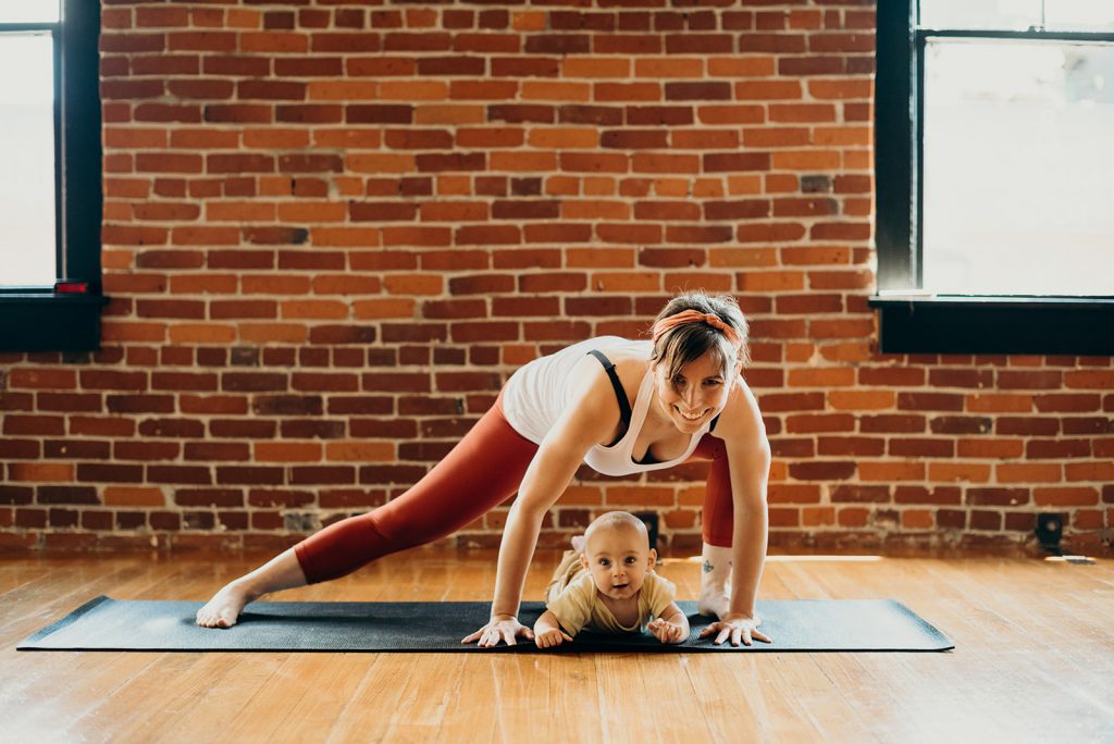 A new mother and her baby are practicing postpartum yoga at MamaSpace Yoga.