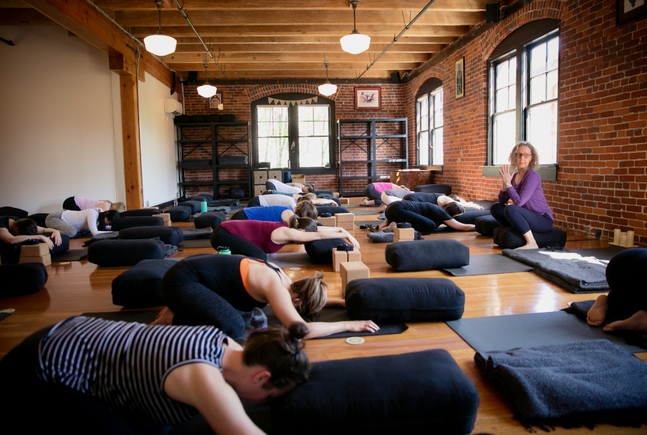 A Large Group of Pregnant Students Practices Child's Pose at MamaSpace Yoga With Carol Gray Leading the Class