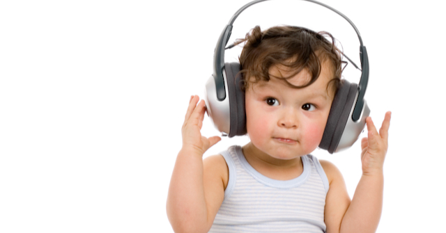 A photo of a toddler wearing headphones pretending to listen to a podcast