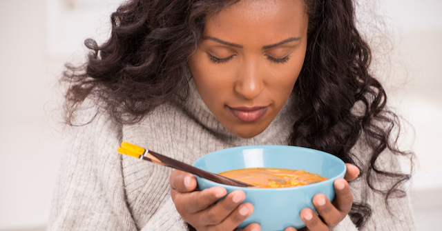 A photo of an African American woman about to eat some soup