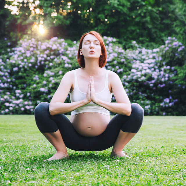 A photo of a pregnant woman squatting outdoors