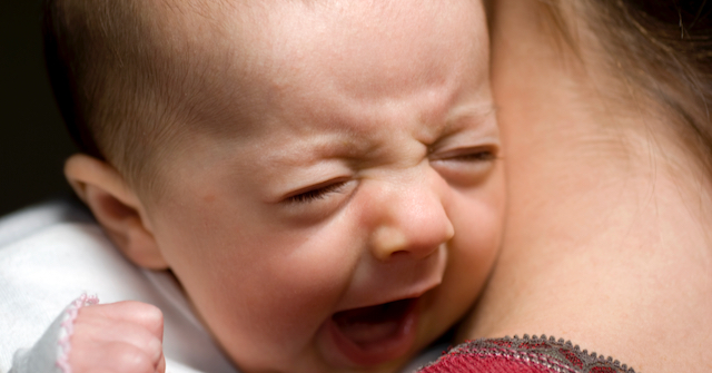 A photo of a parent hloding a crying baby over their shoulder