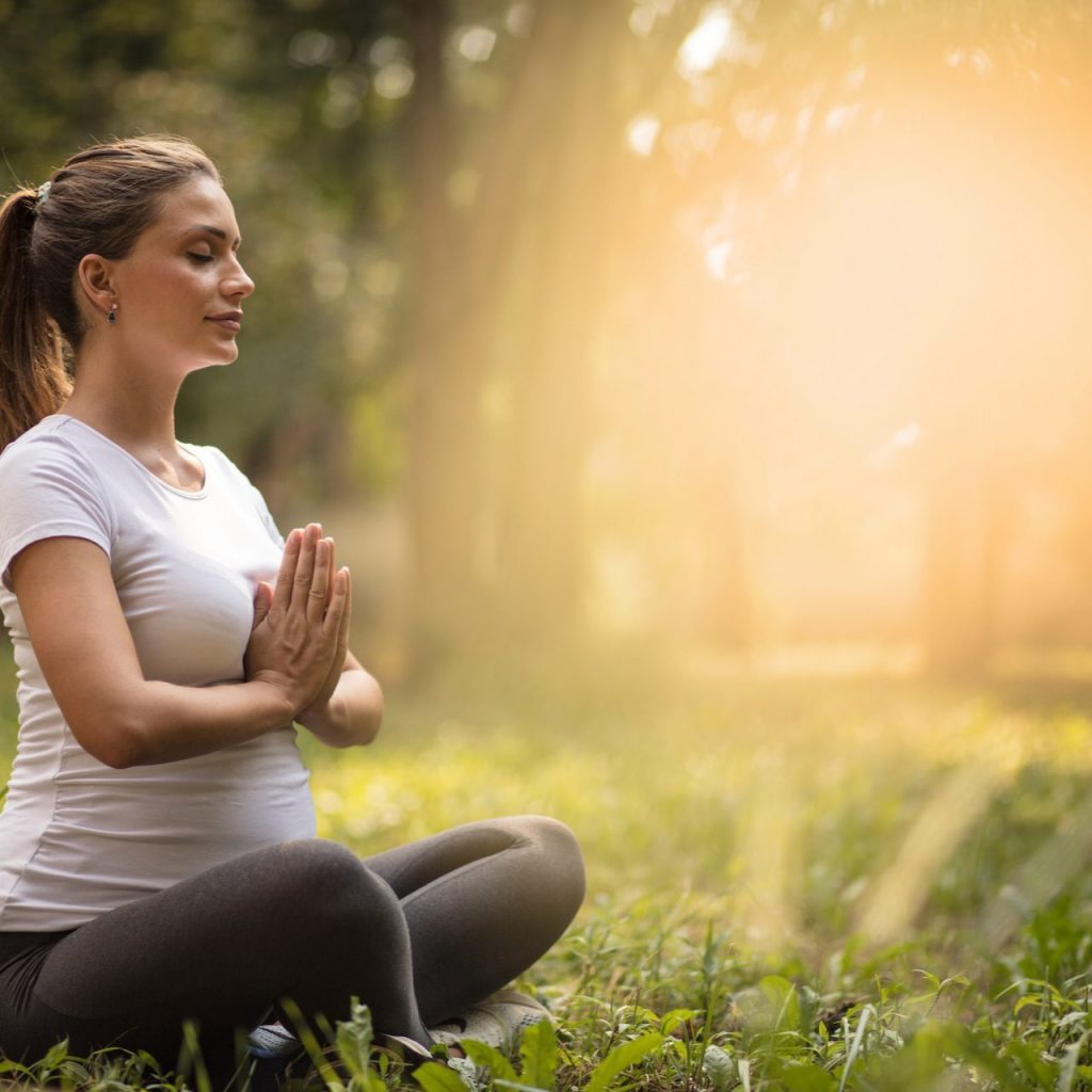 A pregnant woman meditating outdoors