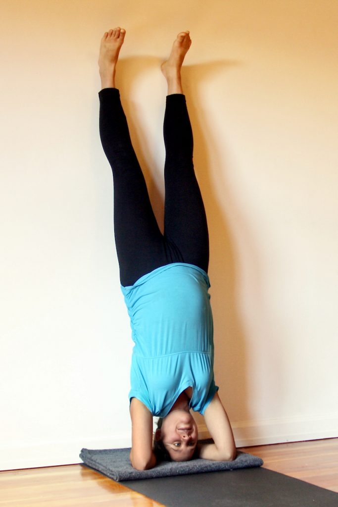 A opregnant student using the wall for headstands at MamaSpace Yoga