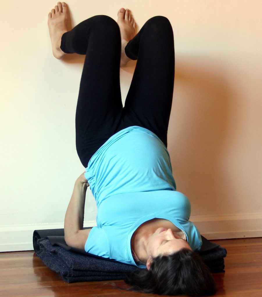 A pregnant student demonstrating Supported Shoulder Stand using the wall at MamaSpace Yoga