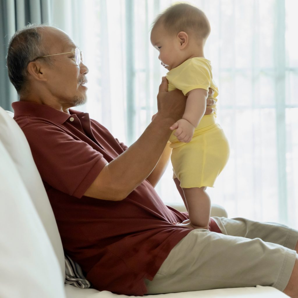 Photo of a man holding a baby in a standing position in his lap